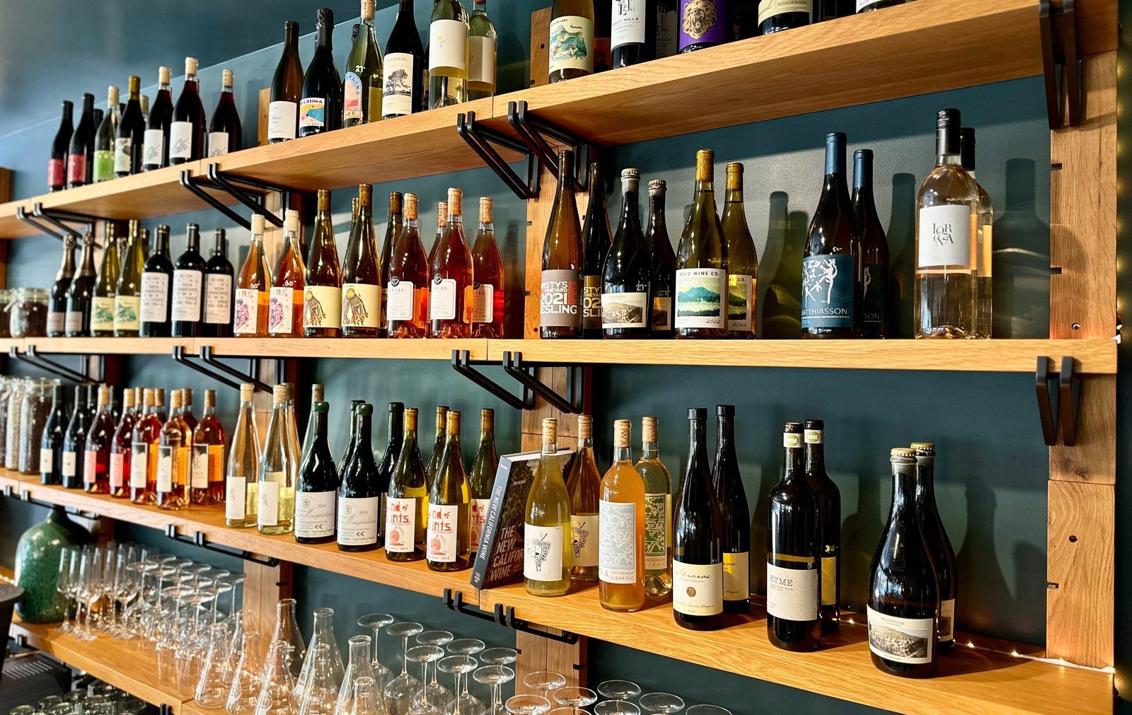Wine bottles and glassware along the wood shelves at Therapie Bistro